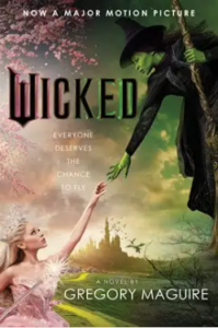 Front cover of the book Wicked shows a still from the 2024 movie, with Glinda the Good Witch of the North (Ariana Grande) reaching up to touch the hand of the Wicked Witch of the West (Cynthia Erivo), the Emerald City is visible in the background