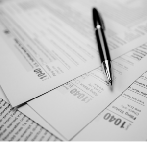 Black and white image of U.S. 1040 tax forms with an ink pen