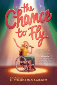 Book cover for The Chance to Fly by Ali Stroker and Stacy Davidowitz which features a blonde girl in a wheelchair singing into a microphone as a spotlight shines on her.