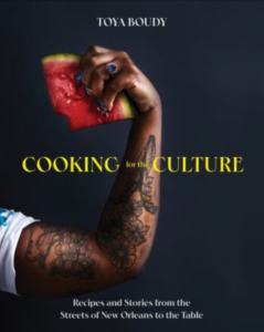 Front cover of Cooking for the Culture showing only the tattooed, flexed arm of author Toya Boudy. In her hand, which has a sapphire ring on one finger, she's clutching a wedge of watermelon