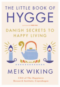 Front cover of The Little Book of Hygge: Nordic-styled illustrations of two lighted candlesticks and a kettle on the flame